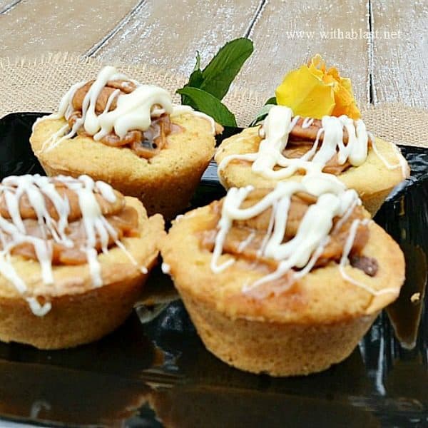 Quick, easy and delicious Cookie Cups filled with Chocolate Chips, chopped Pecans, Caramel and topped with another Pecan Nut and drizzled with White Chocolate 